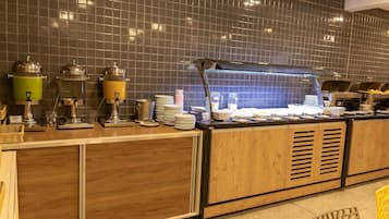 Montaje de bufé con dispensadores de comida, platos y una vitrina de vidrio.