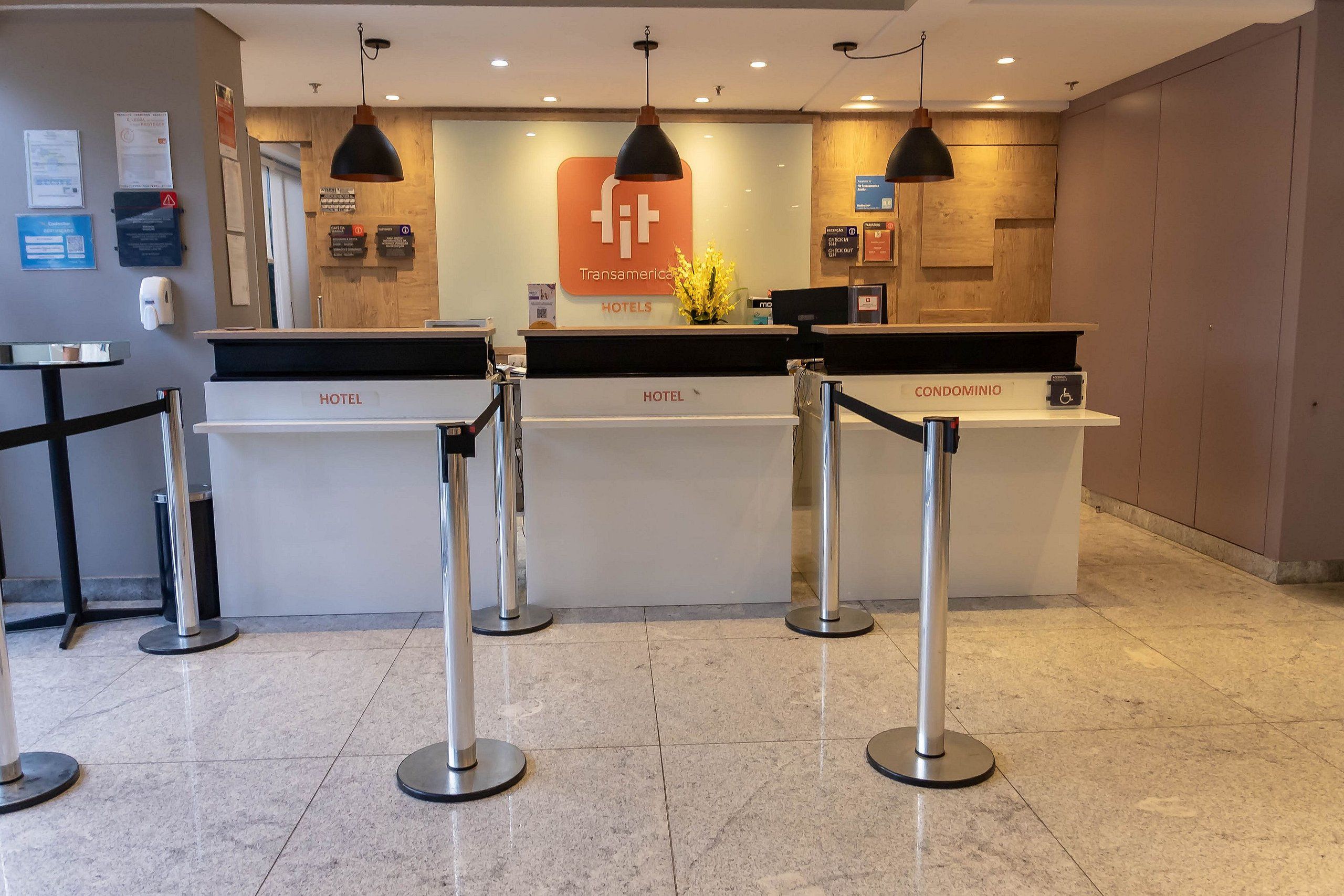 Un comptoir d’accueil d’hôtel avec un logo, une enseigne indiquant « Transamerica Hotels » et une autre indiquant « Condominio ».