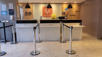 Un comptoir d’accueil d’hôtel avec un logo, une enseigne indiquant « Transamerica Hotels » et une autre indiquant « Condominio ».