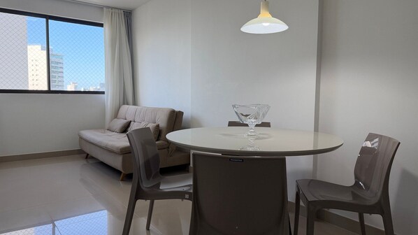 A modern room with a round table, two chairs, a sofa, and a hanging light fixture. - Flats no Beach Class Residence por Yolo  (Recife)