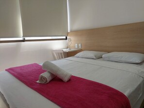 A hotel room with a bed, a wooden headboard, a nightstand, and a window with blinds. - Flats no Beach Class Residence por Yolo (Recife)