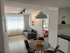 Une chambre d’hôtel moderne équipée d’un canapé, d’une table à manger et d’un coin cuisine.