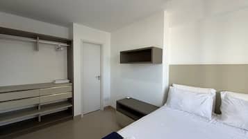 Une chambre d’hôtel comprenant un lit, une armoire, une table de chevet et une étagère fixée au mur.