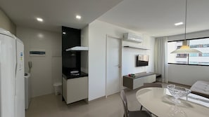 Una cucina moderna con forno integrato, microonde e macchina del caffè. C'è una zona pranzo con tavolo e sedie, e una finestra con vista sugli edifici.