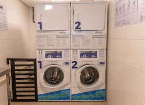 A laundry facility with two washing machines, numbered 1 and 2, and a drying rack. Instructions and symbols for use are displayed above each machine. - Flats no Beach Class Residence por Yolo (Recife)