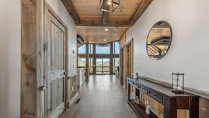 A hallway with wooden doors, a mirror, and a console table with a lantern.