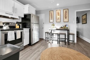 Una cocina moderna con armarios blancos, electrodomésticos de acero inoxidable y una zona de comedor de madera.