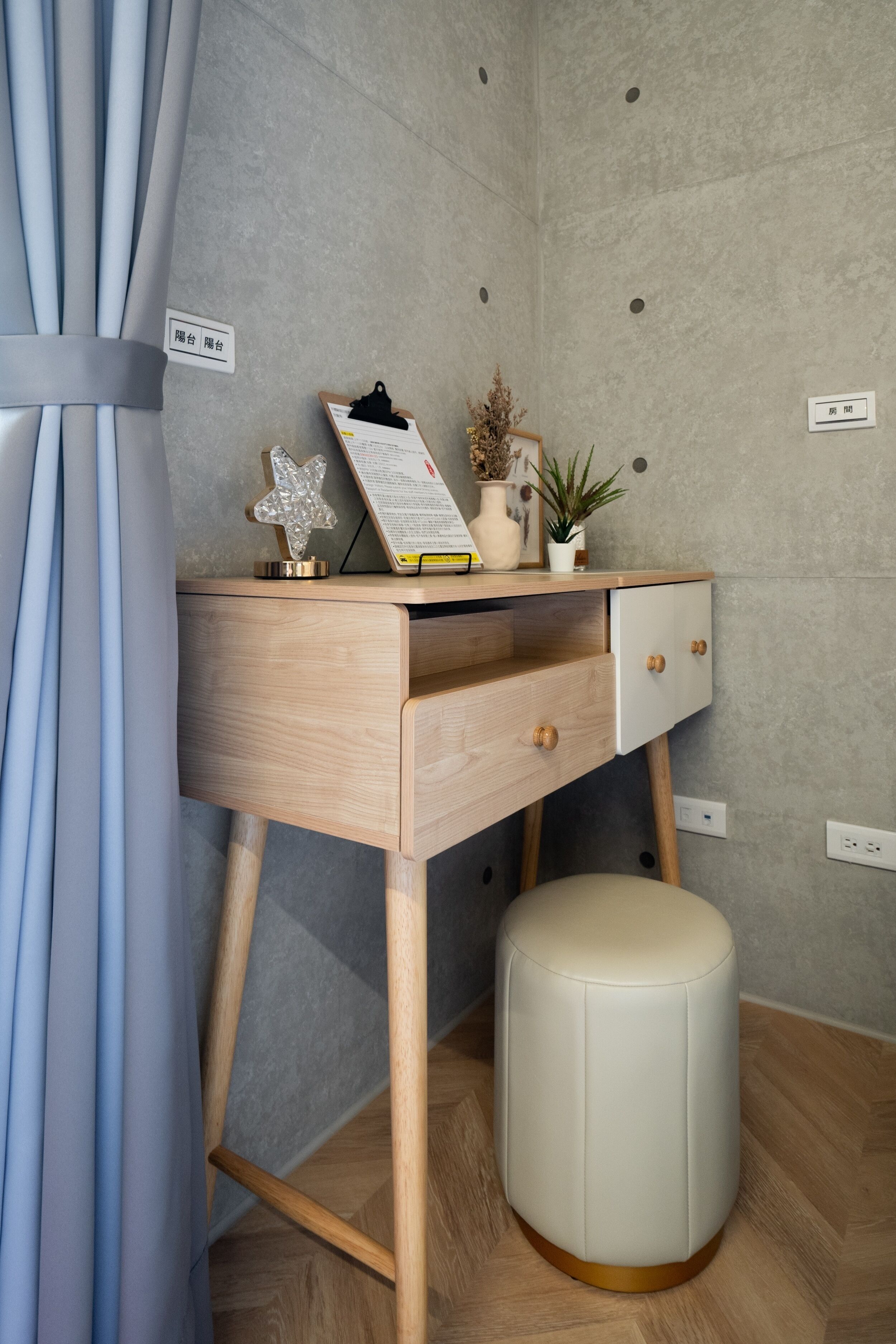 Una camera moderna con una scrivania in legno, uno sgabello e una mensola a parete con oggetti decorativi.