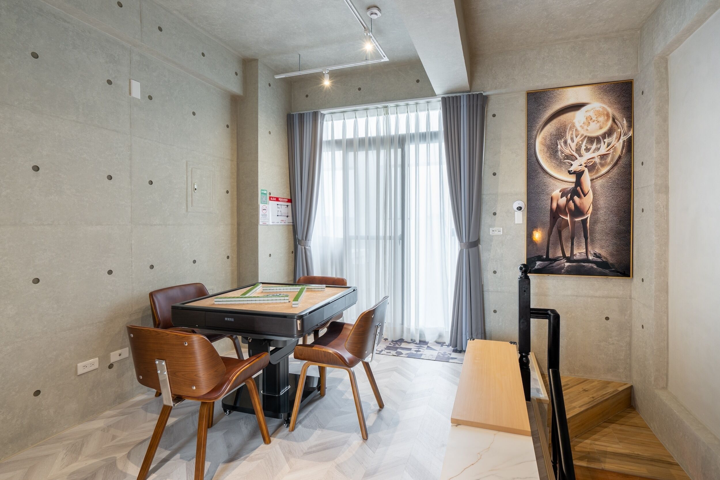 A modern dining area with a table and chairs, a large window with curtains, and a wall-mounted artwork.