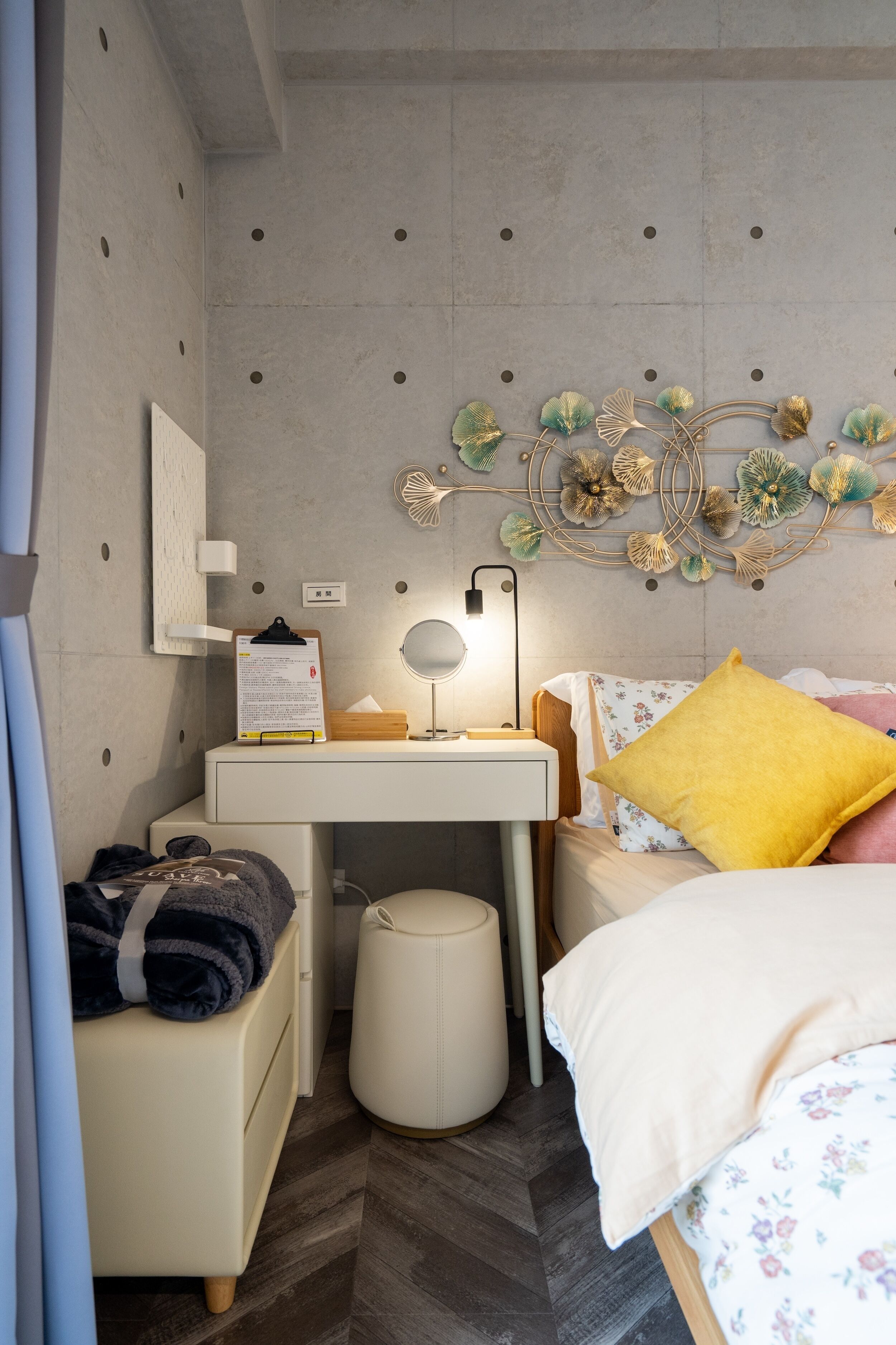 A bedroom with a bed, bedside table, lamp, and a decorative wall piece.