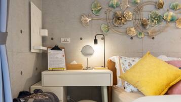 A bedroom with a bed, bedside table, lamp, and a decorative wall piece.