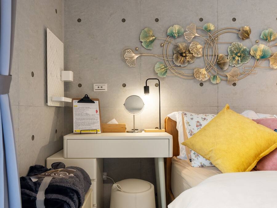 A bedroom with a bed, bedside table, lamp, and a decorative wall piece.