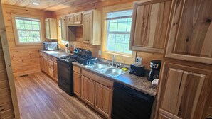 Cocina de cabaña de madera con estufa, fregadero y lavavajillas.