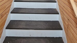 Una escalera de madera con escalones blancos que conduce a un techo con un adorno con forma de oso.