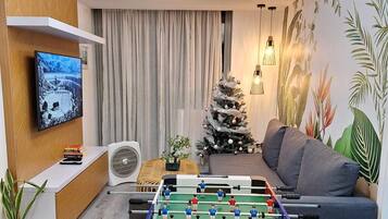 A living room with a foosball table, a TV, a sofa, and a Christmas tree.