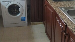A compact kitchen with a washing machine, microwave, and sink. - 4-bed Apartment in Costa del Silencio (Arona)