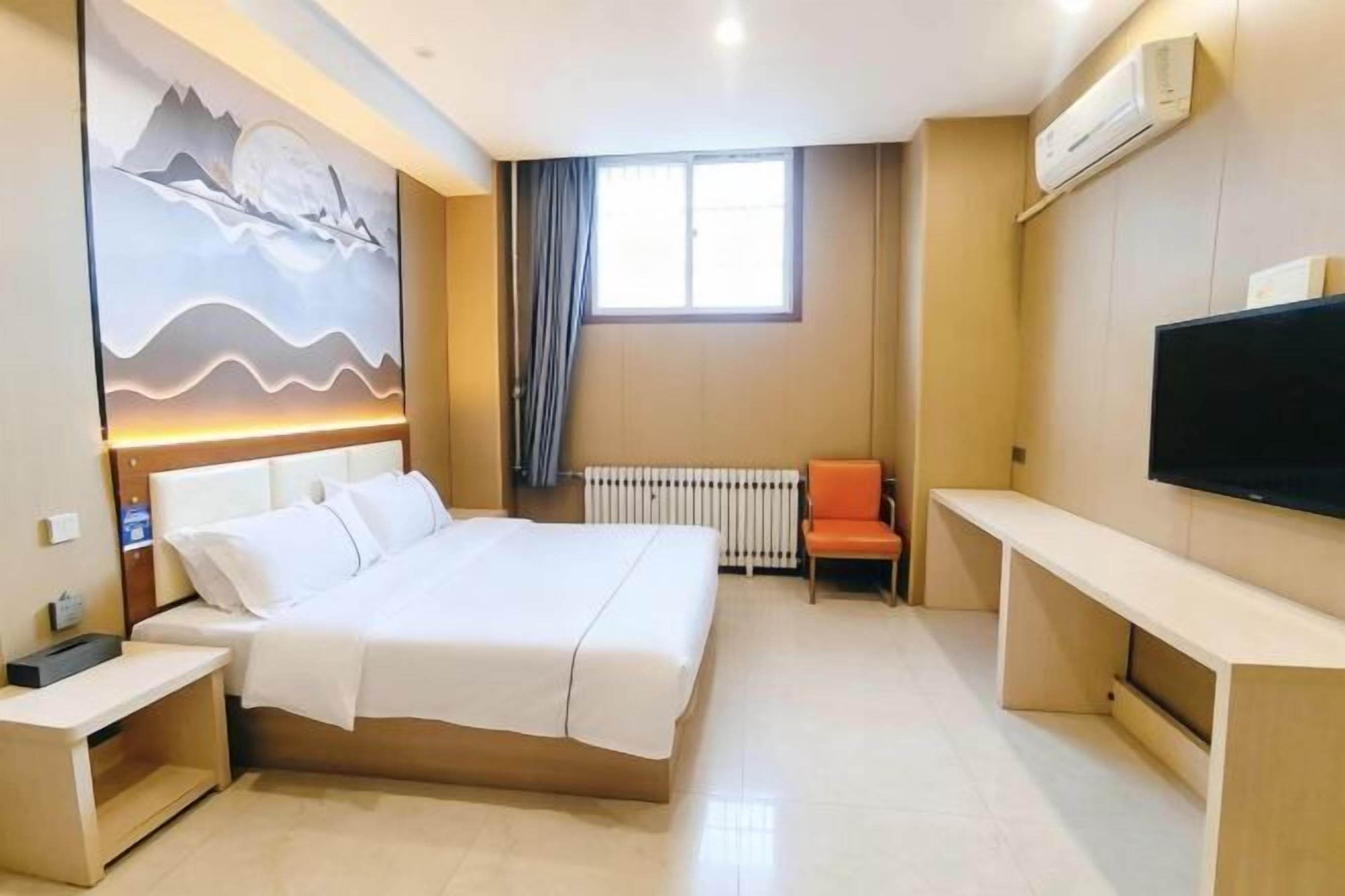 A hotel room with a bed, bedside table, TV, and a window with curtains.