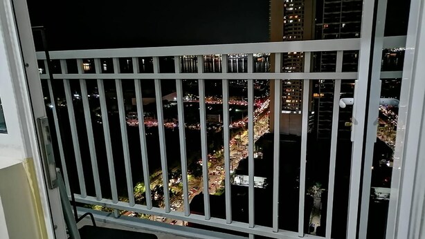 Ein Balkon mit Metallgeländer und Blick auf eine nächtliche Stadtlandschaft.