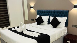 A modern hotel room with a large bed, black and white bedding, and a blue headboard. - THE LOTAZ HOTEL (Kanayannur)