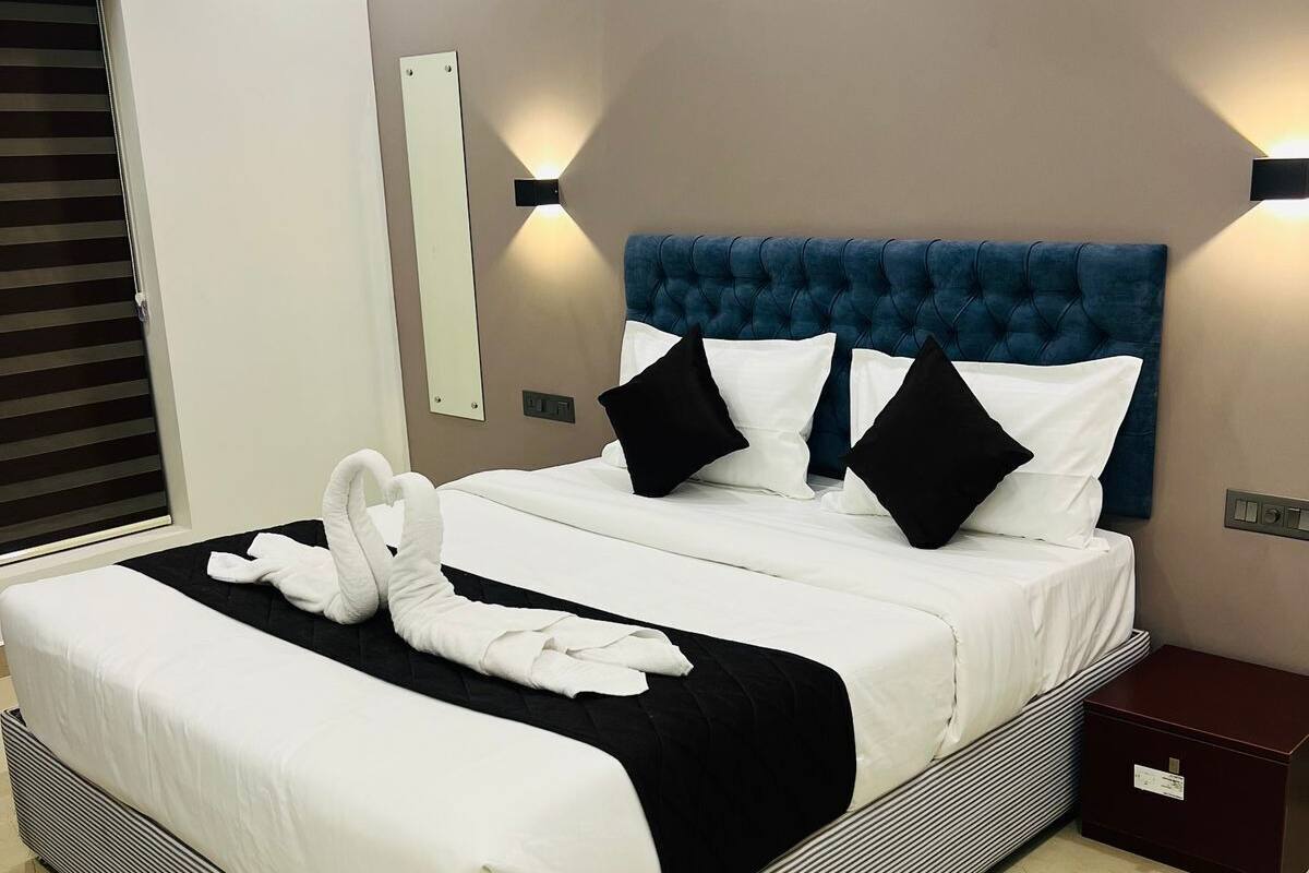 Een moderne hotelkamer met een groot bed, zwart-wit beddengoed en een blauw hoofdeinde.