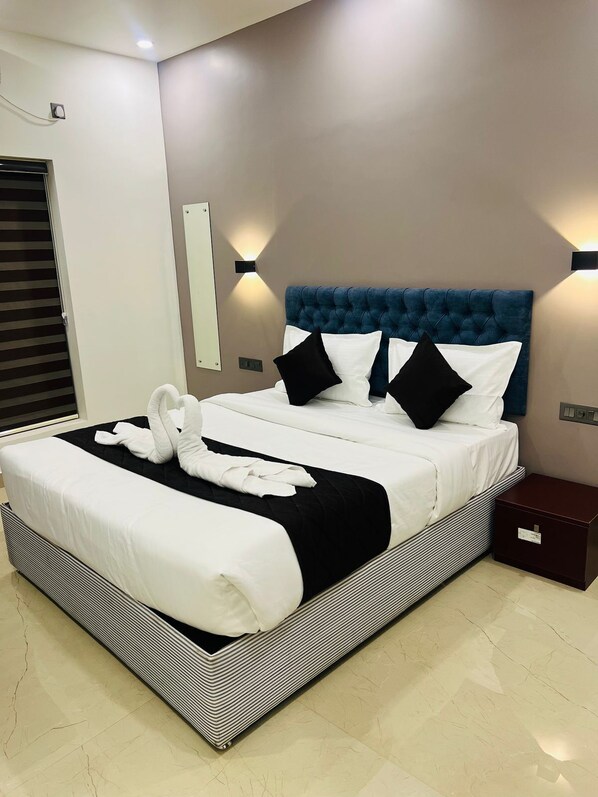 A modern hotel room with a large bed, black and white bedding, and a blue headboard. - THE LOTAZ HOTEL (Kanayannur)