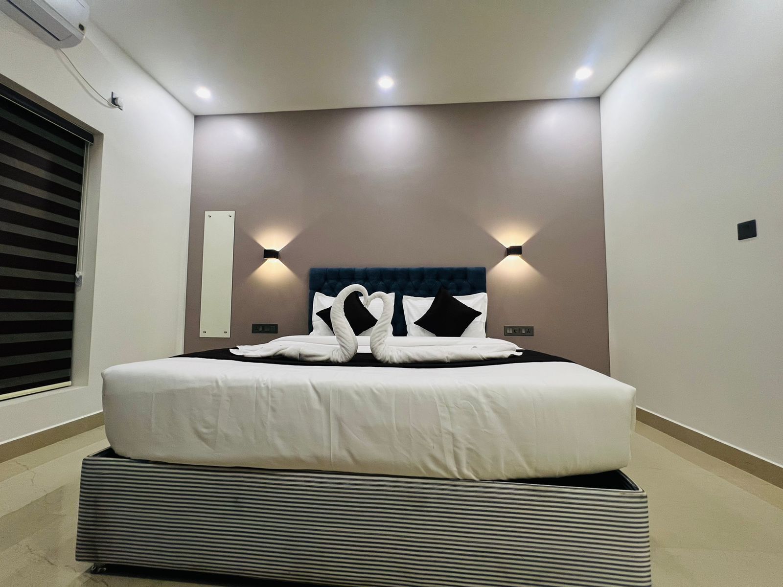 A modern hotel room with a large bed, two wall-mounted lights, and a headboard with a tufted design.