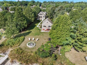 A residential property with a large lawn, a fire pit, and a two-story house with a garage. - Downtown Baileys Harbor Waterfront: Limestone Edge (Baileys Harbor)