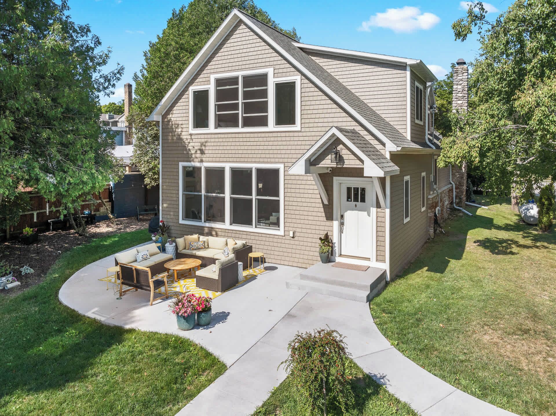 A two-story house with a front porch, a covered patio, and a well-maintained lawn.