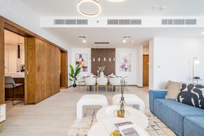 A modern living room with a dining area, white furniture, and a blue sofa.