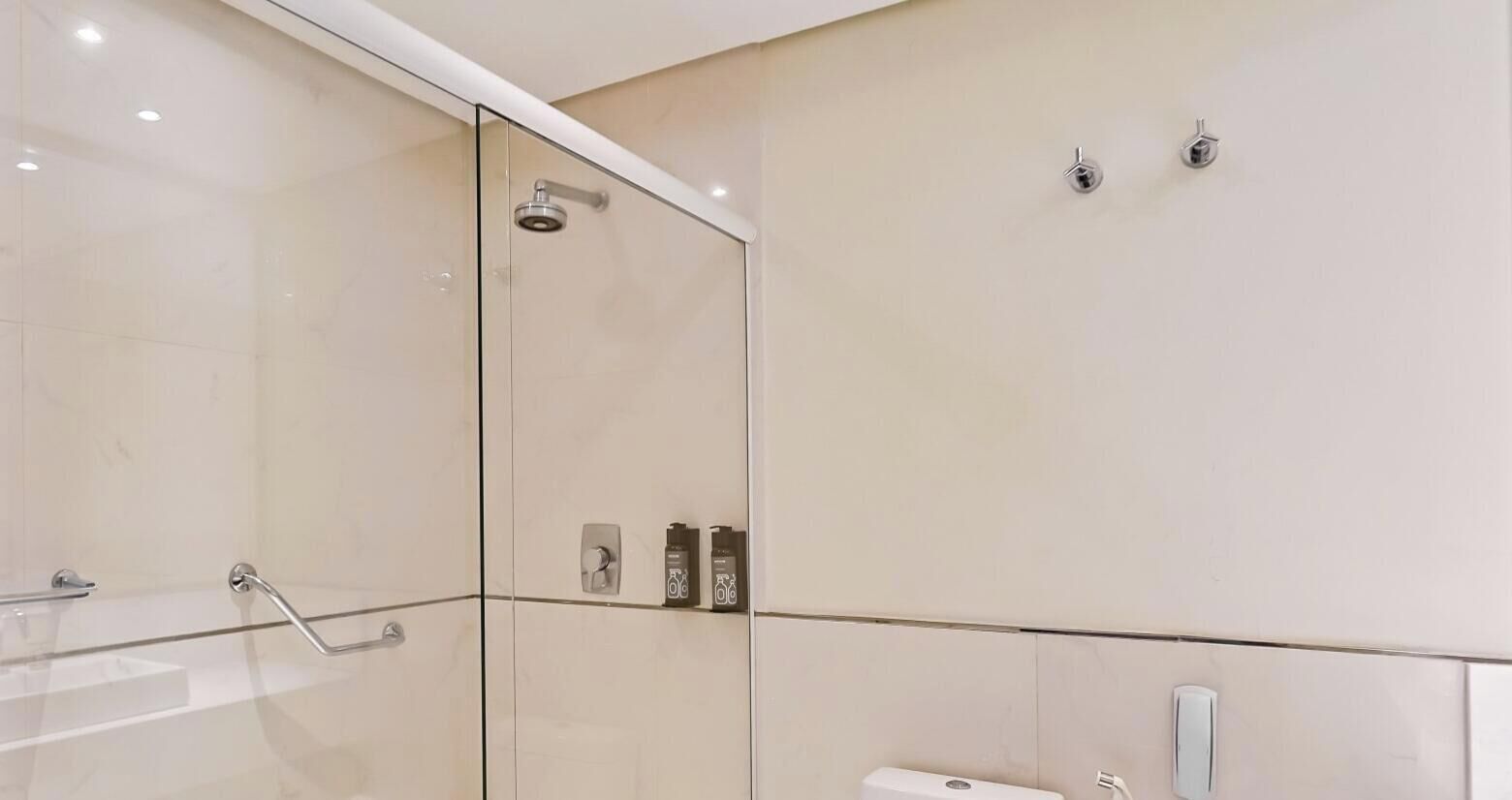 Uma casa de banho moderna com cabine de duche em vidro, sanita e lavatório.