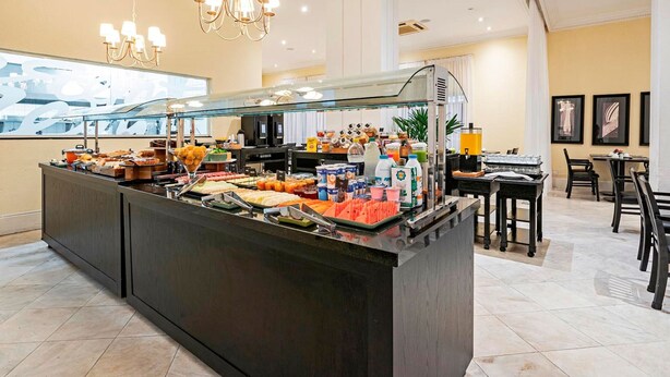 Ein Bereich mit Buffet, verschiedenen Speisen und Getränken, einer Sitzgelegenheit mit Tischen und Stühlen sowie einem Kronleuchter.
