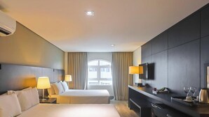 Een hotelkamer met een bed, nachtkastjes, een televisie en een raam met gordijnen.