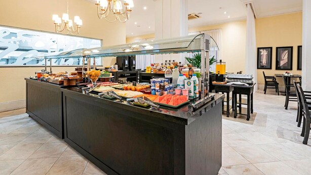 Ein Bereich mit Buffet, verschiedenen Speisen und Getränken, einer Sitzgelegenheit mit Tischen und Stühlen sowie einem Kronleuchter.