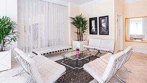 Una sala de estar moderna con un sofá blanco, una mesa de centro de vidrio y un espejo grande.