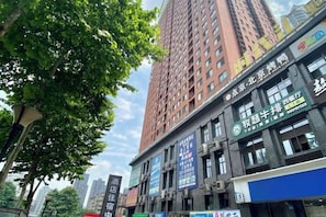 A high-rise building with multiple commercial establishments on the ground floor, including a restaurant and a shop with a blue awning.