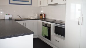 Une cuisine moderne avec des meubles blancs, un plan de travail noir, une cuisinière et un évier.