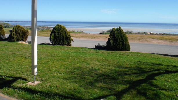 A covered outdoor area with a view of the sea and beach.