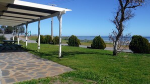 A covered outdoor area with a stone patio, a picnic table, and a view of the ocean and pier.