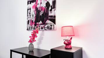 Ein modernes Wohnzimmer mit einem schwarzen Tisch, einer pinken Lampe und einer Vase mit pinken Blumen.