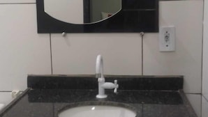 Een badkamer met een wit wastafel, een zwart aanrechtblad en een spiegel erboven.