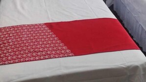 Een hotelkamer met twee bedden, elk met witte lakens en een rood sierkussen.
