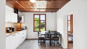 A compact kitchen with white cabinets, a wooden ceiling, and a dining area with a table and chairs.