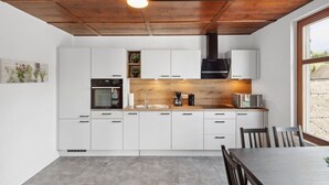 A modern kitchen with white cabinets, a wooden countertop, and a built-in stove.
