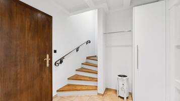 A staircase with wooden steps leading to a landing, a white door, and a white cabinet.