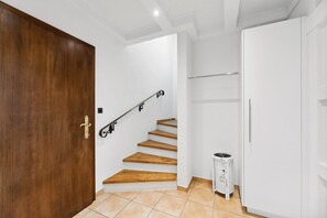 A staircase with wooden steps leading to a landing, a white door, and a white cabinet.