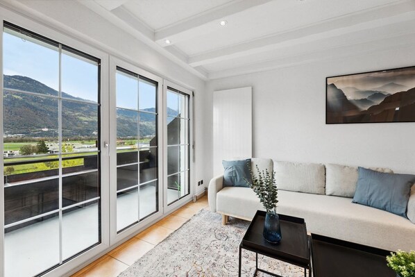 A modern living room with a sofa, a coffee table, and a painting on the wall. - FENUS View over Liechtenstein | Parking | Kitchen (Buchs)