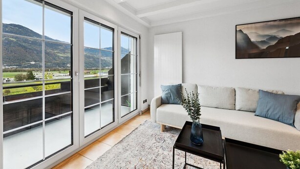 A modern living room with a sofa, a coffee table, and a painting on the wall. - FENUS View over Liechtenstein | Parking | Kitchen (Buchs)