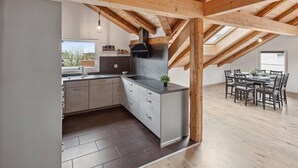 Una cocina moderna con una isla grande, vigas de madera y una zona de comedor con mesa y sillas.