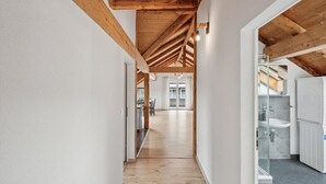 Un pasillo con vigas de madera y vista a una habitación con un lavabo y armarios.