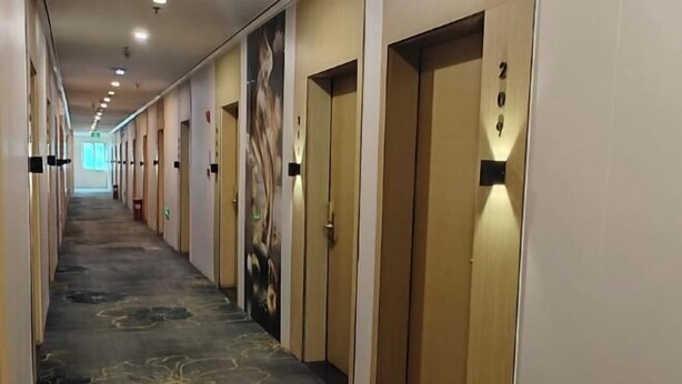A hotel corridor with doors numbered 201 to 210, carpeted with a floral pattern, and a large abstract mural on the wall. - Yi Mi Hotel Shenzhen Longgang Pinghu South China City (Shenzhen)